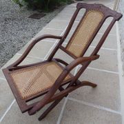 Antique folding chair with caned seat and backrest made of wood.