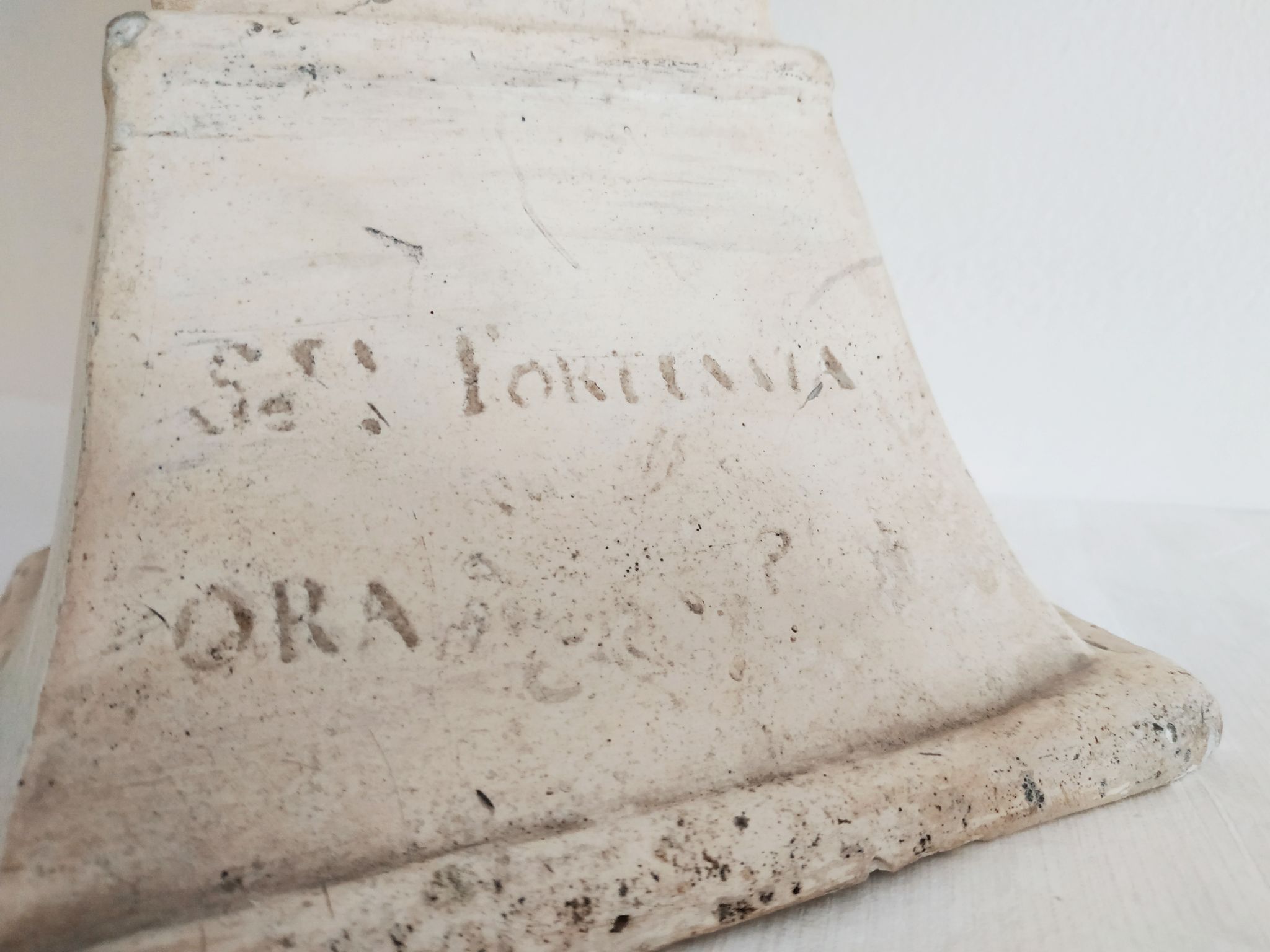 Bust of woman in plaster on pedestal with inscription