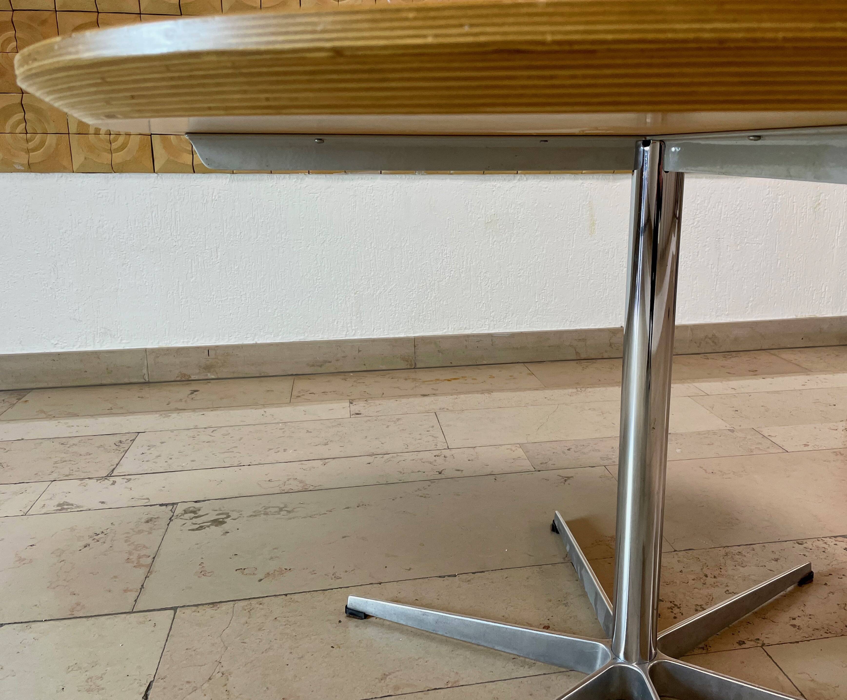 Dining table with a star-shaped six-legged base by Arne Jacobsen for Fritz Hansen.
