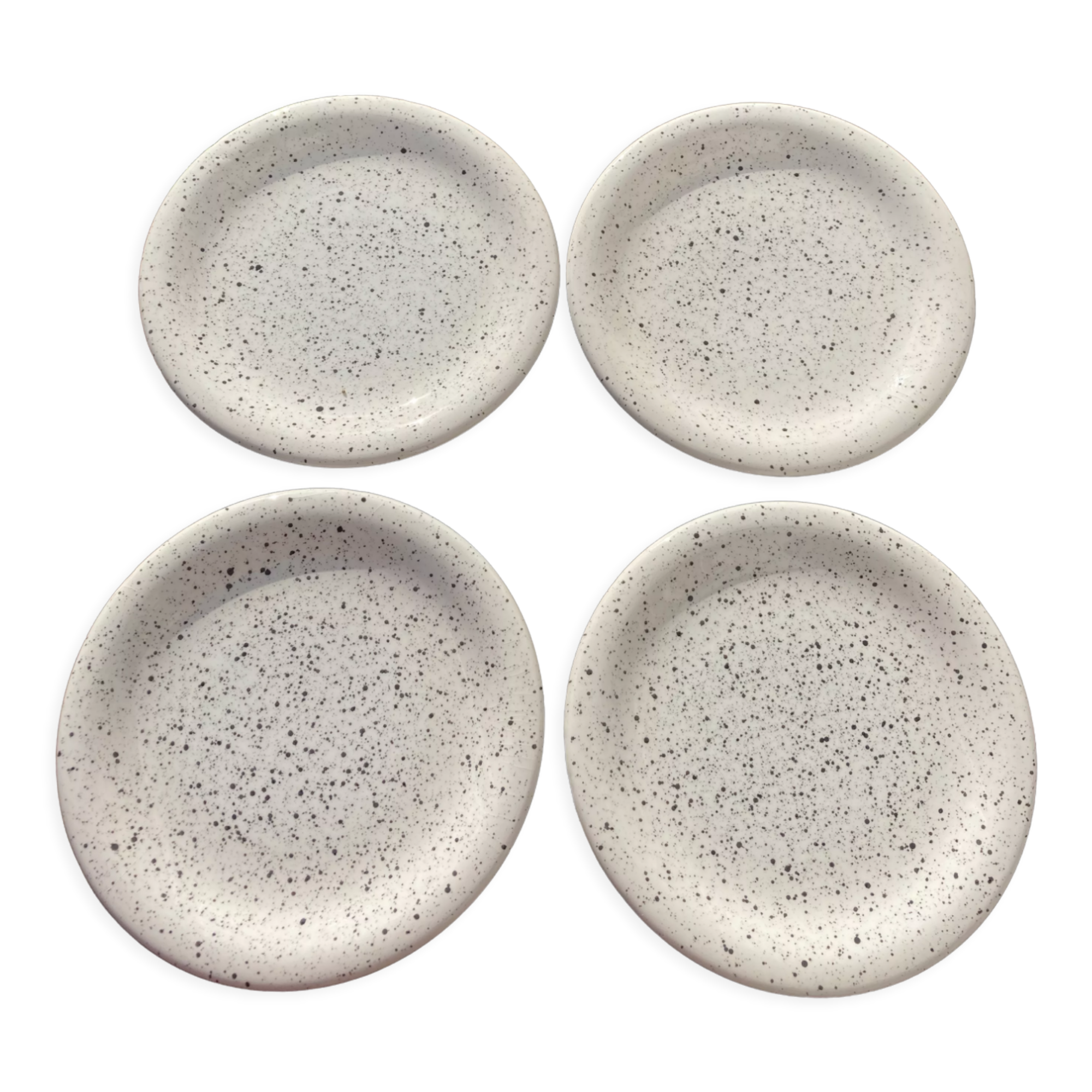 4 black speckled dessert plates on a vintage white background