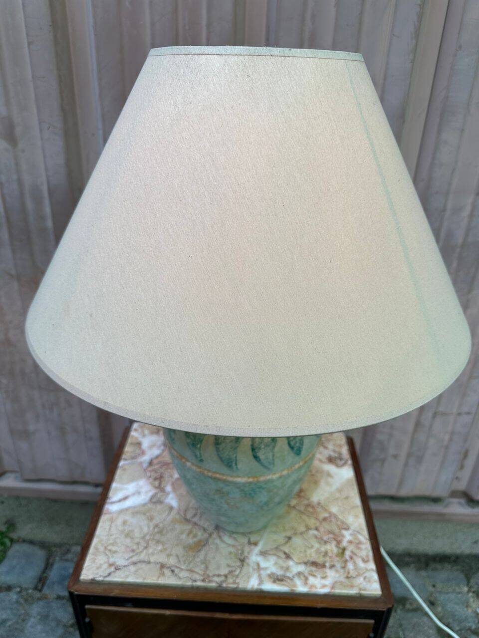 Vintage green ceramic table lamp with a worn lampshade.