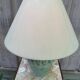 Vintage green ceramic table lamp with a worn lampshade.