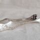 Antique silver-plated sugar tongs with lion's paws.