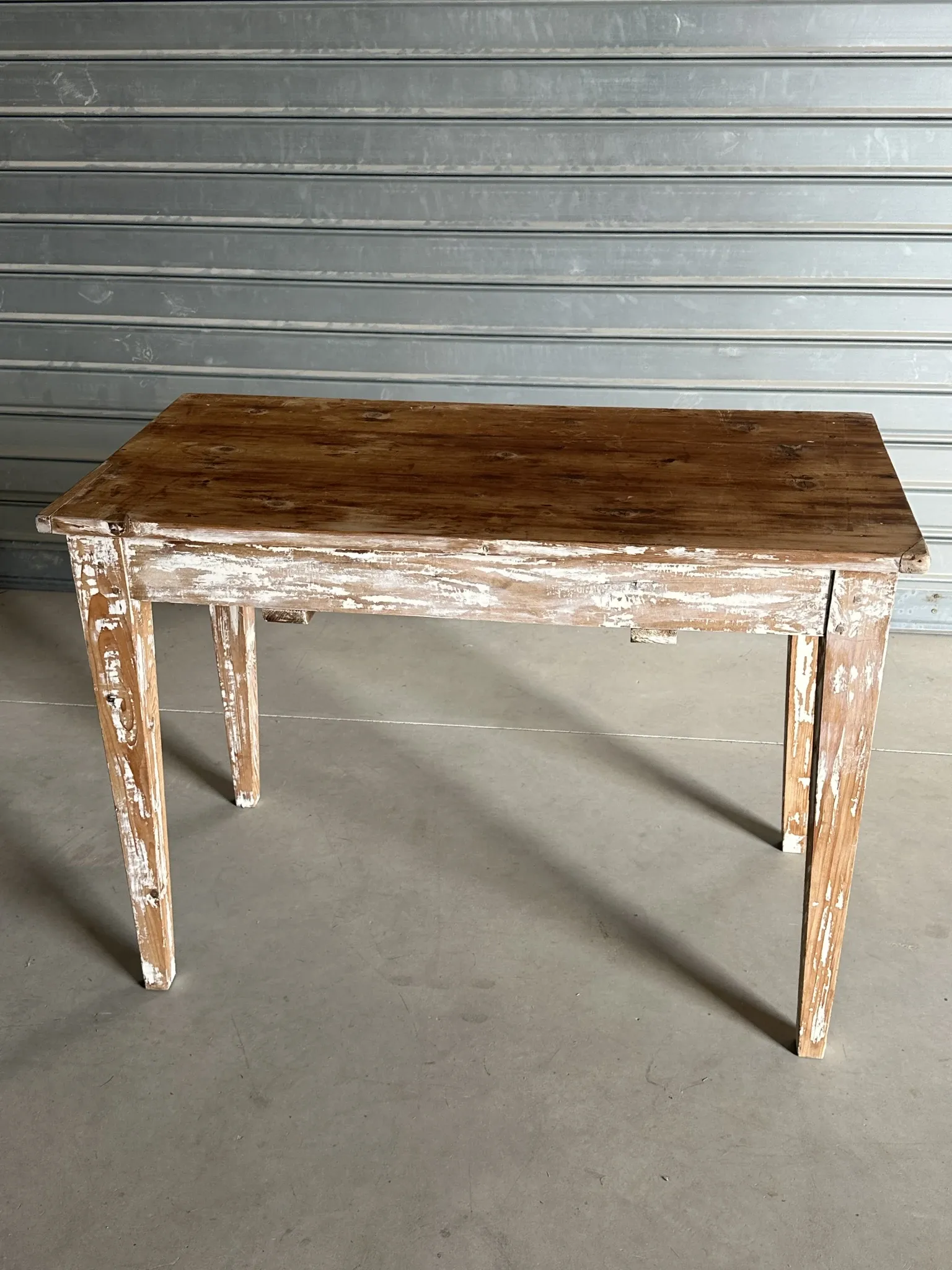 Vintage table made of raw wood with a distressed white base.