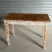 Vintage table made of raw wood with a distressed white base.