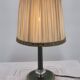 Brass table lamp with green patina and empire-style fabric shade.
