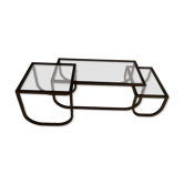 Table basse asymétrique en métal et verre avec un cadre architectural courbé.