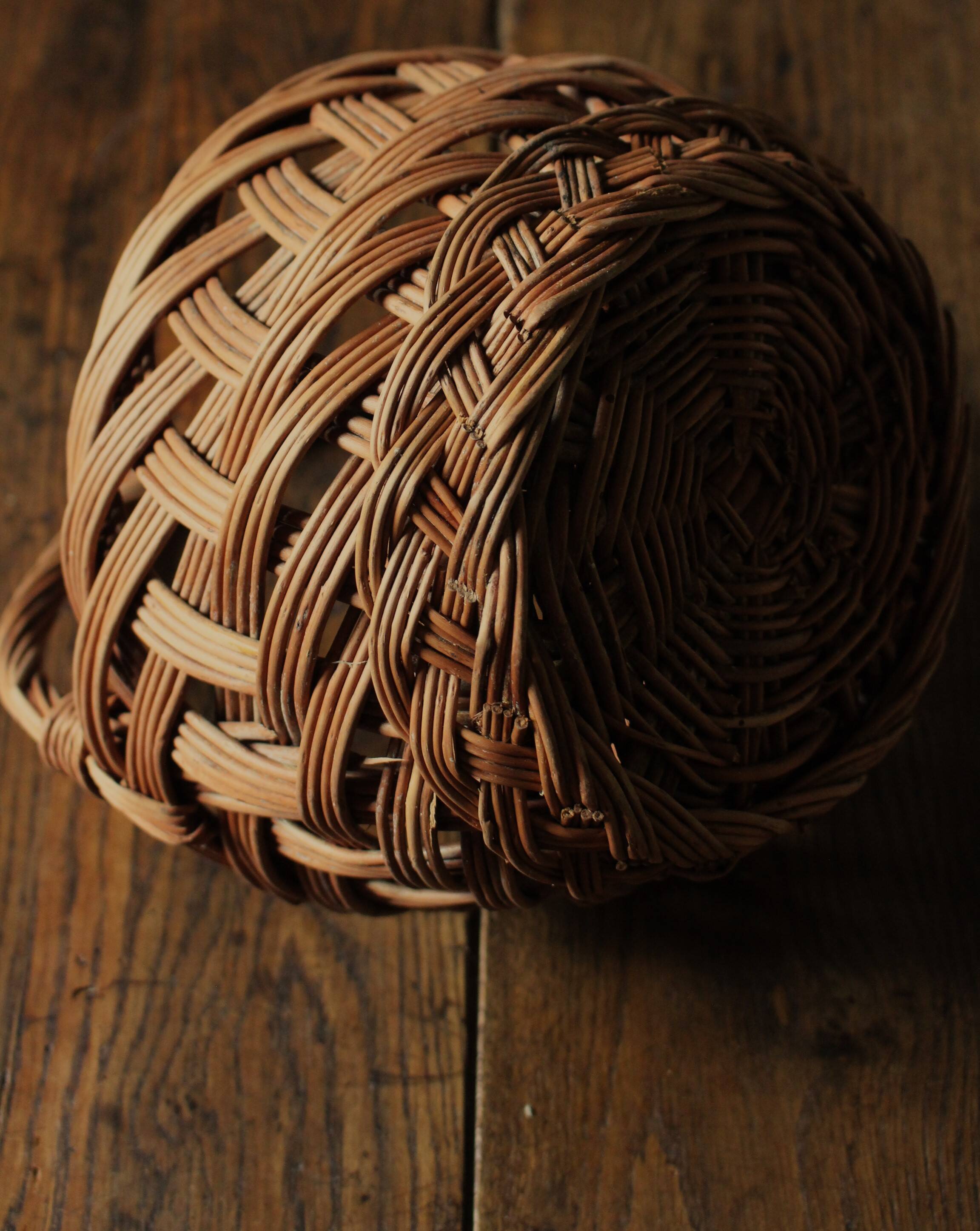Round woven dark wicker basket with openwork vintage handle
