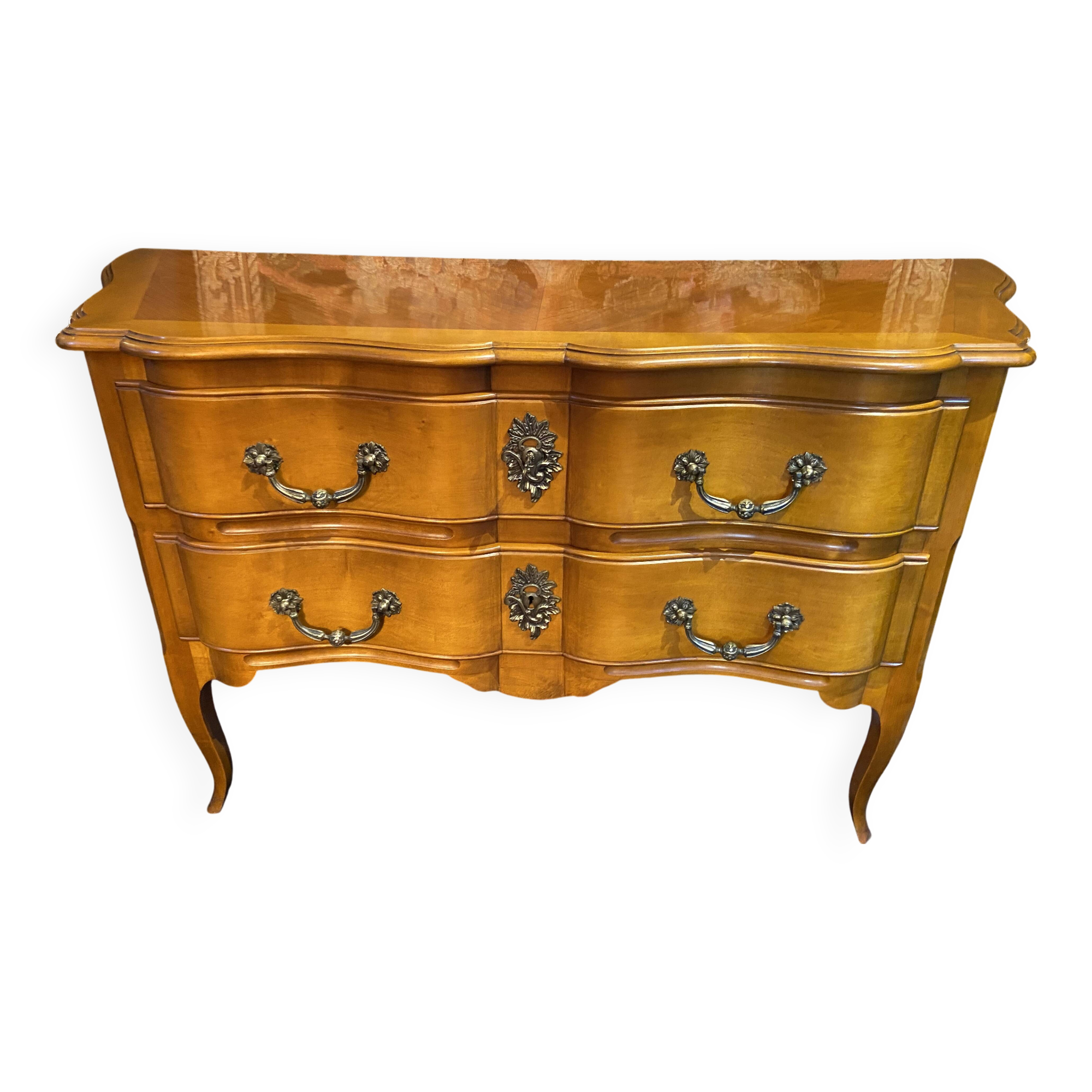 Large bow-fronted chest of drawers in blonde cherry with bronze ornamentation.