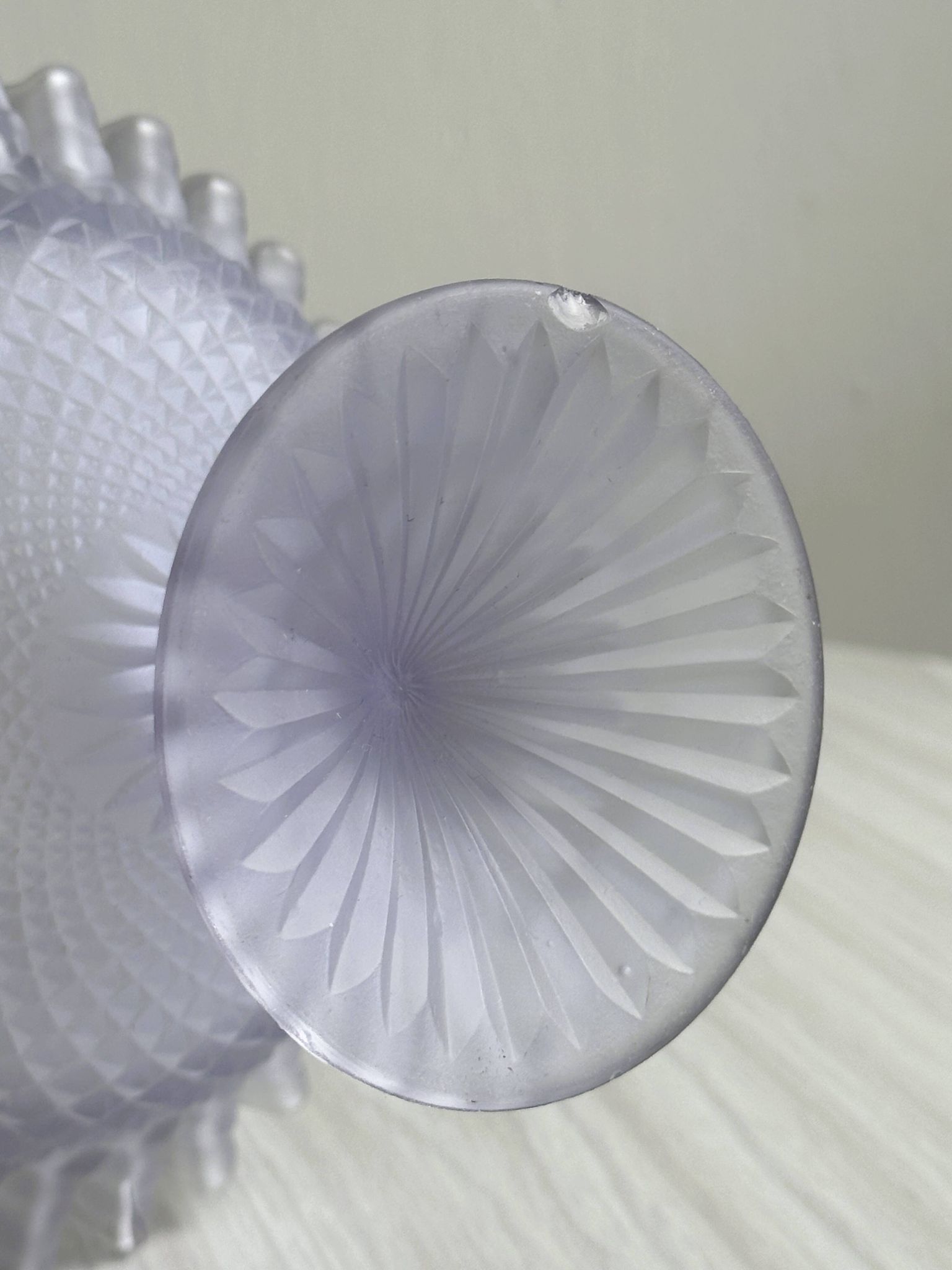 Purple glass pedestal bowl with wavy border and relief pattern.