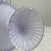 Purple glass pedestal bowl with wavy border and relief pattern.