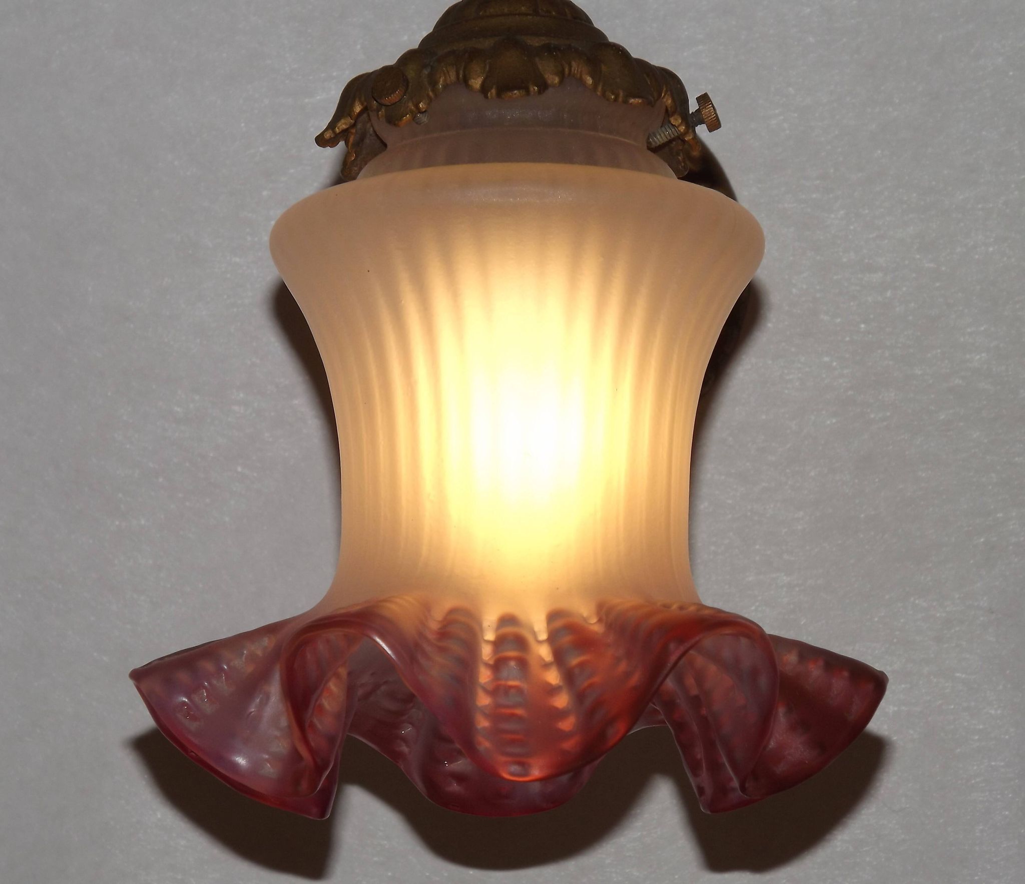 French Art Nouveau wall sconce in bronze with a white and pink glass shade.