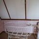 Wrought iron crib painted white from around 1920 with bedding.