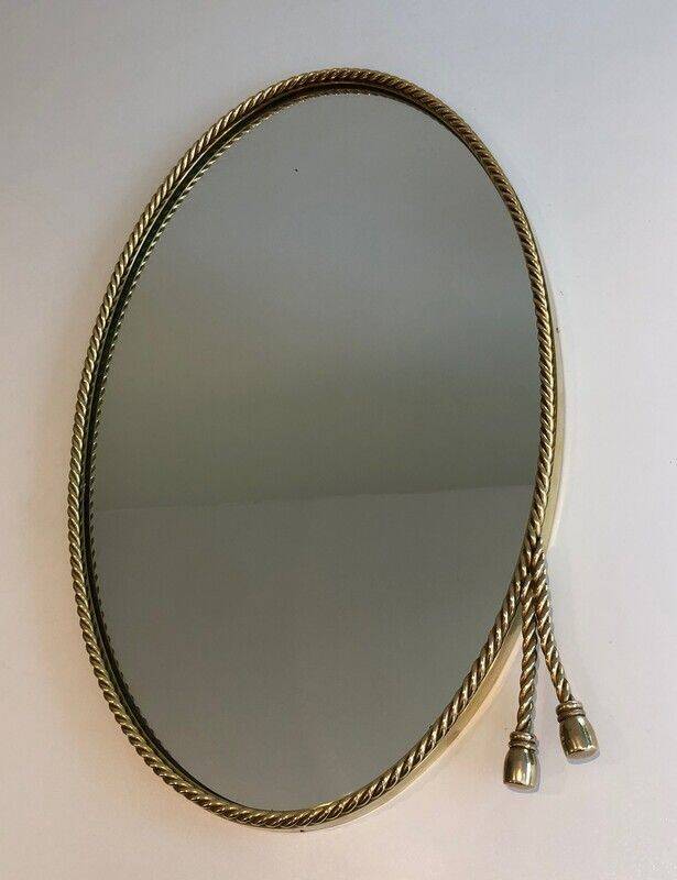 Oval brass mirror surrounded by a cord.