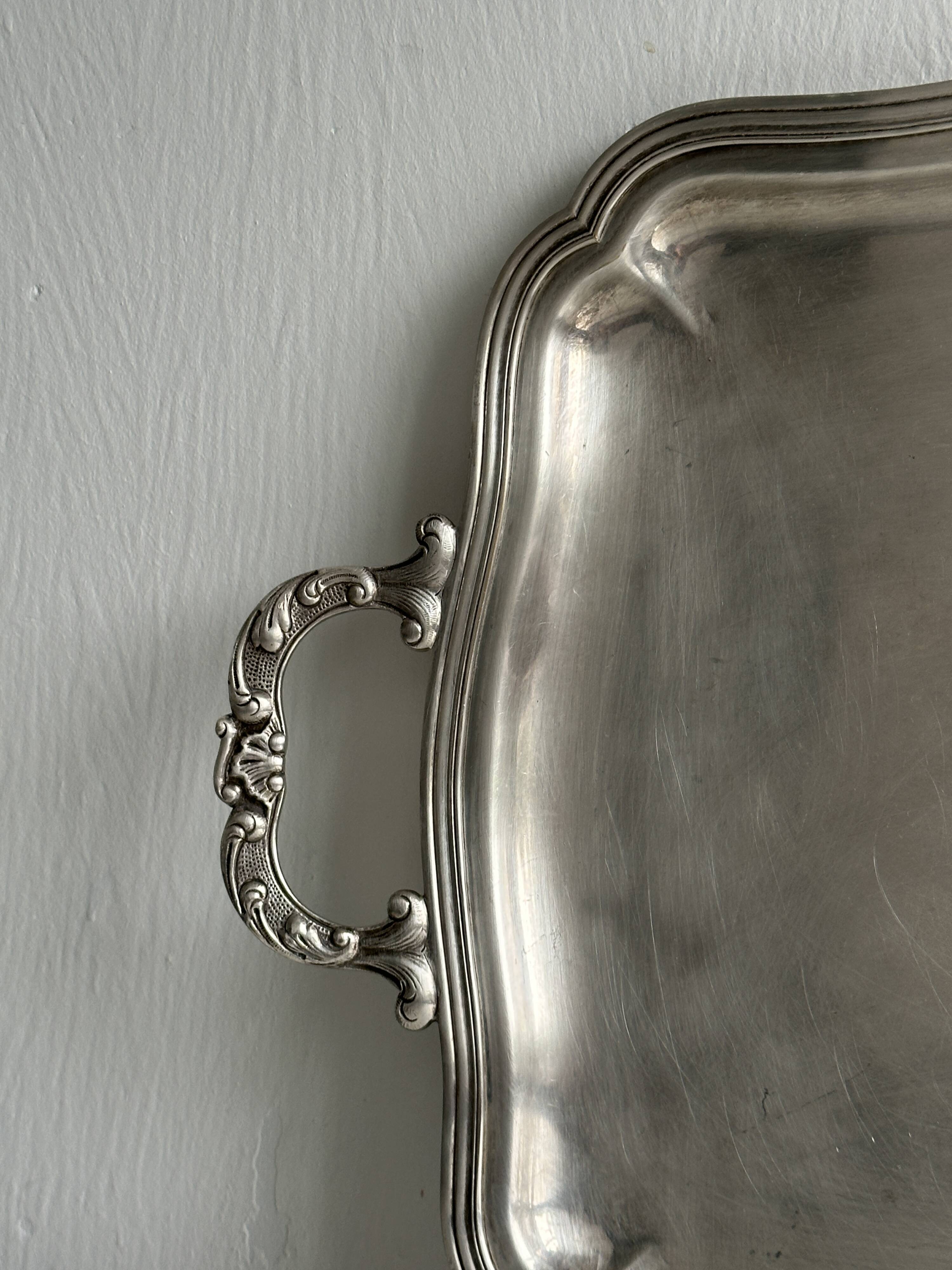 Silver metal serving tray with sculpted handles