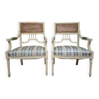 a pair of caned armchairs in the Louis XVI style, elegant and full of charm.