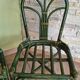 Round rattan table with glass top and 4 green rattan chairs.