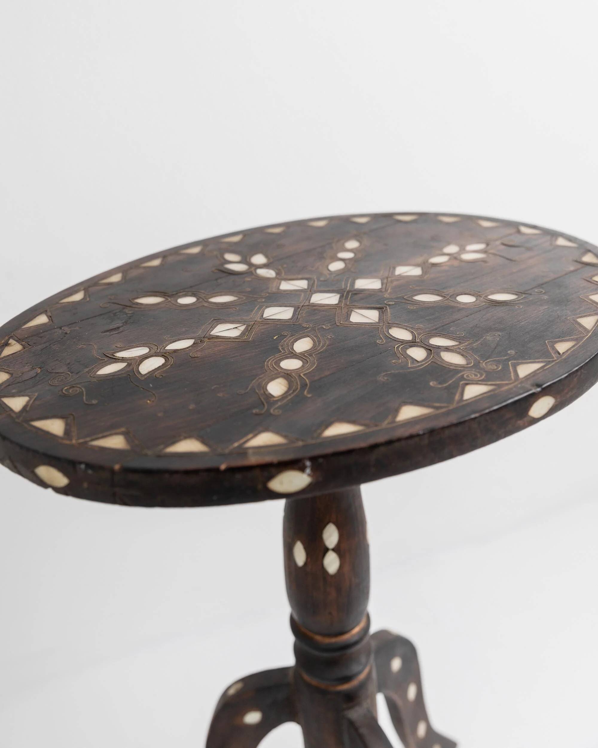 Vintage side table from the early 19th century, dark wood with mother-of-pearl inlays, oval shape with three legs, ethnic style.