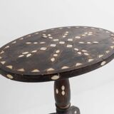Vintage side table from the early 19th century, dark wood with mother-of-pearl inlays, oval shape with three legs, ethnic style.