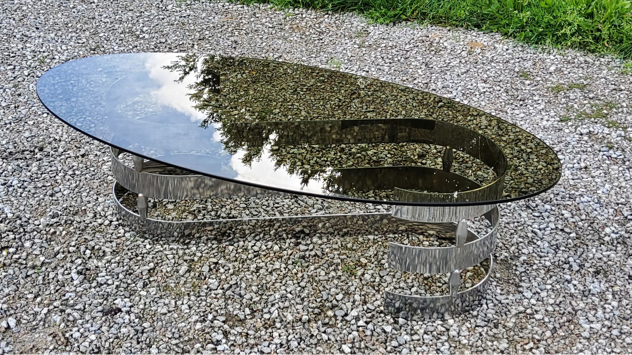Oval coffee table of the 70s chromed metal base in s smoked glass top