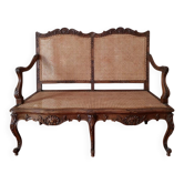 Antique carved solid wood bench with wicker caning.