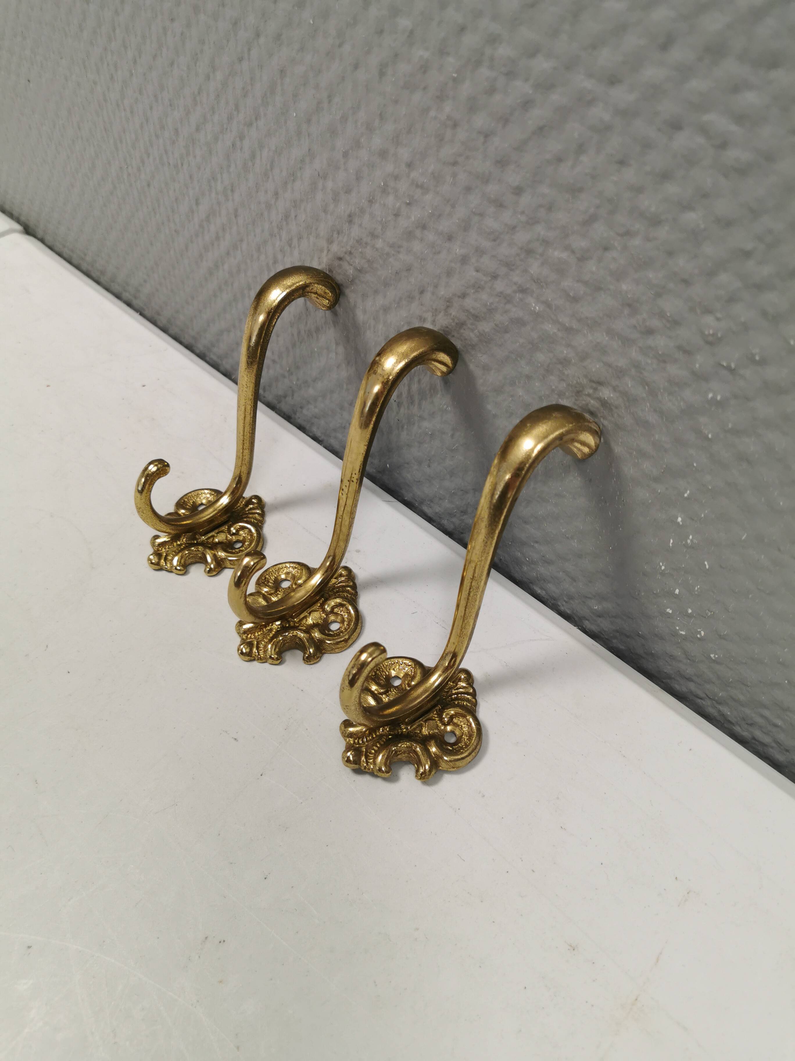Three old and beautiful brass hooks with decorative motifs