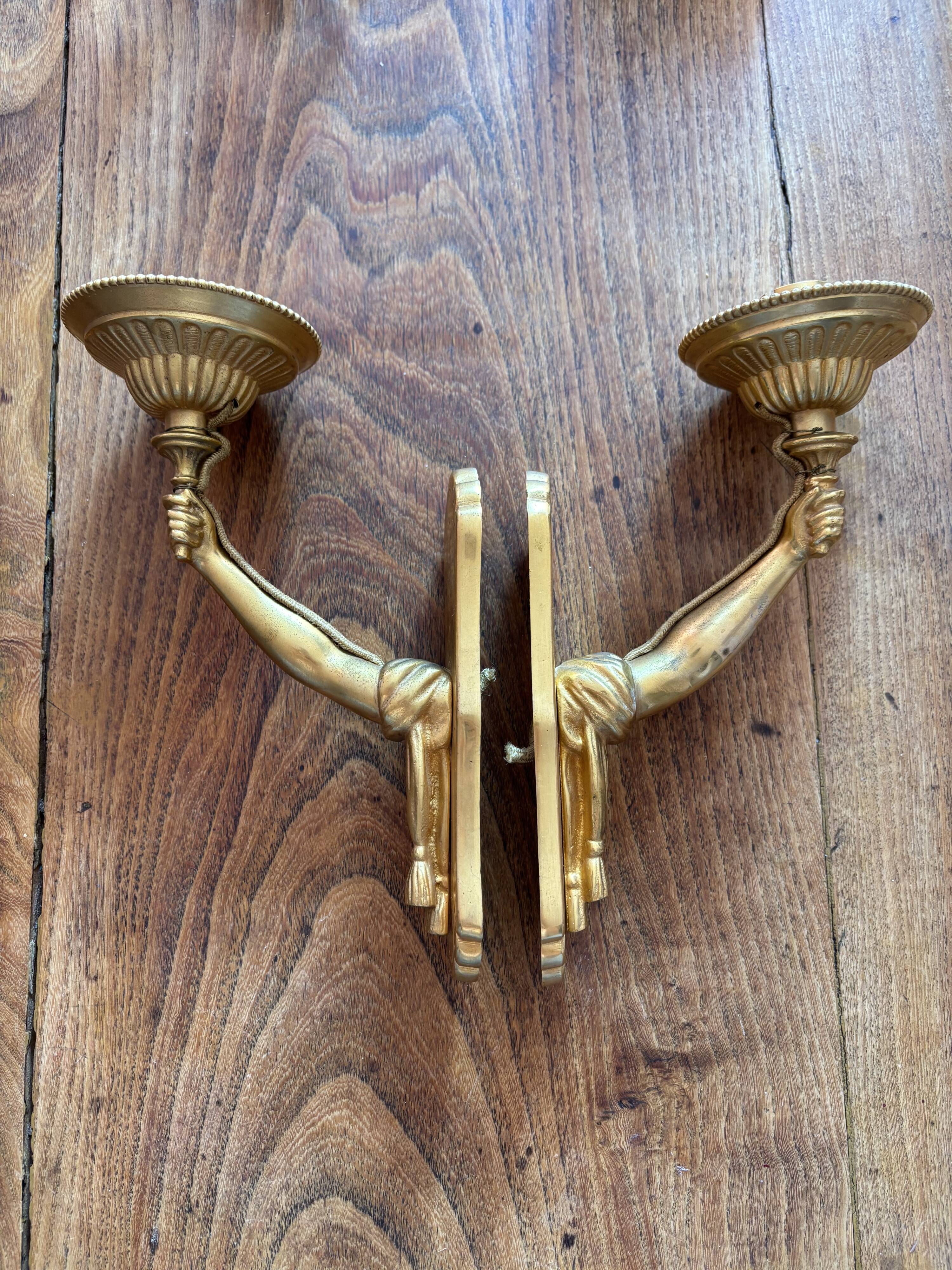 Pair of bronze wall sconces with outstretched arms and hands