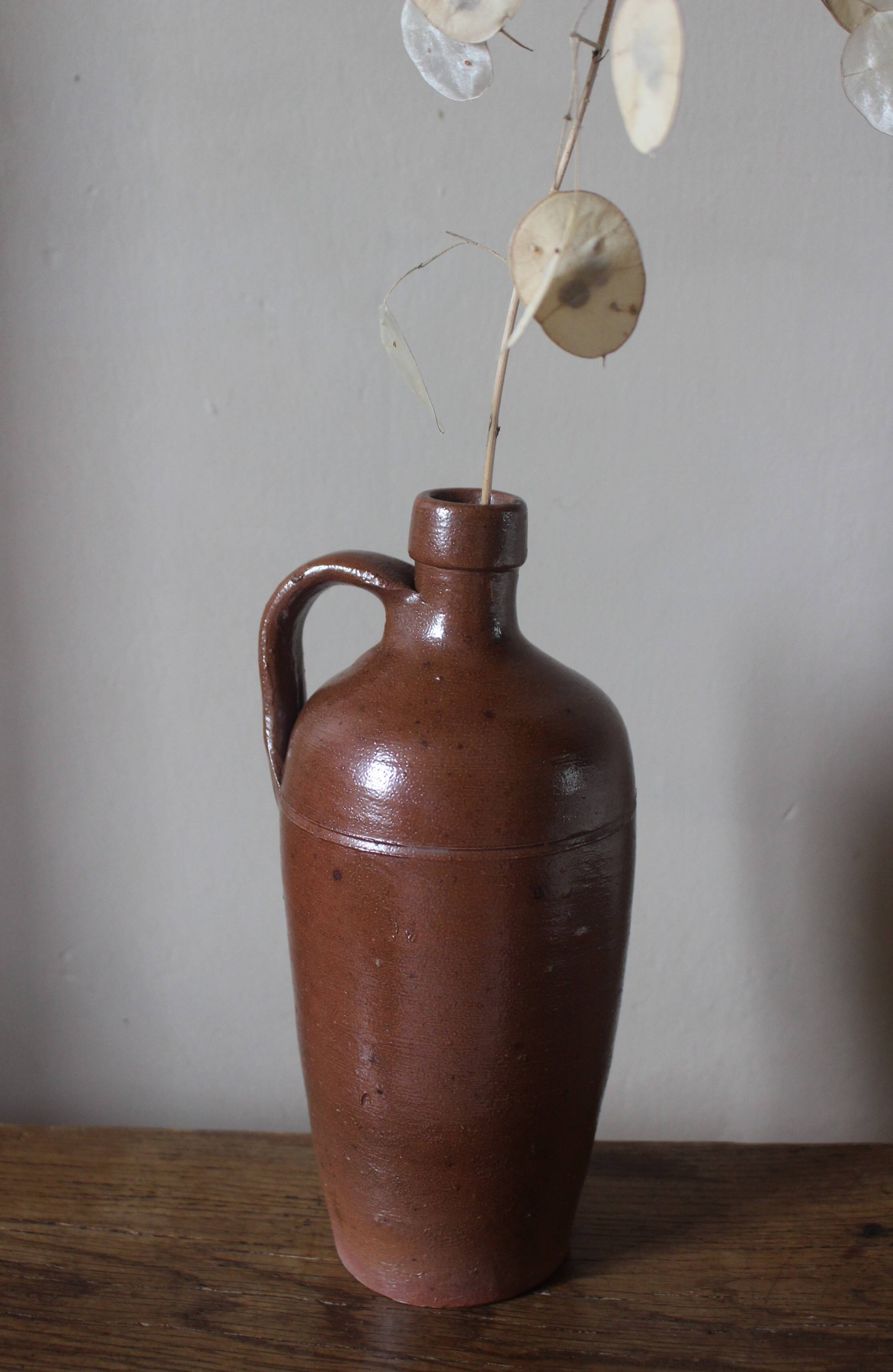 Vintage stoneware liqueur bottle with handle and spout.