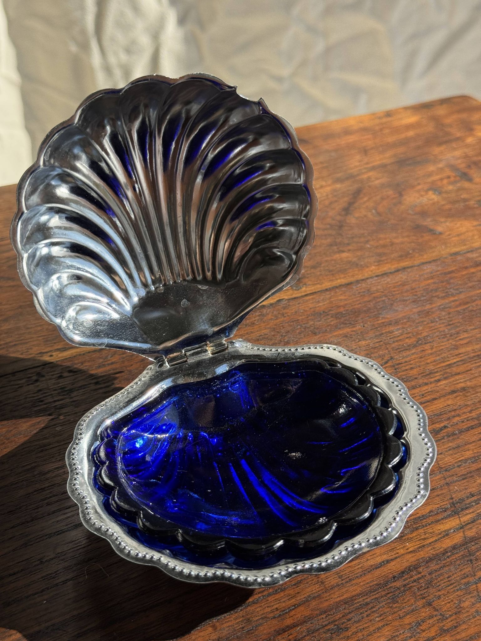Vintage silver-plated shell butter dish with blue bowl.