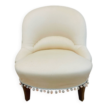 Pale pink upholstered armchair with wooden legs.