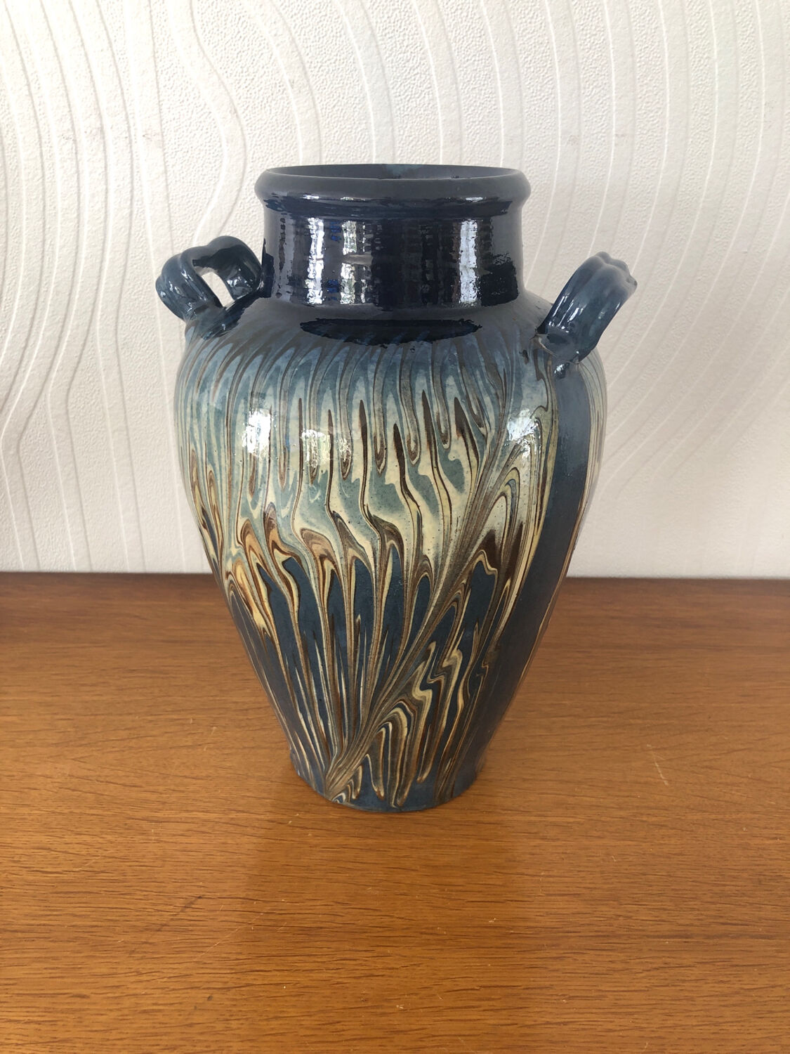 Vase in glazed ceramic decoration drips on blue background