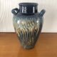 Vase in glazed ceramic decoration drips on blue background