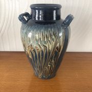Vase in glazed ceramic decoration drips on blue background