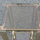 Pair of Hollywood Regency side tables in gold metal and smoked glass.