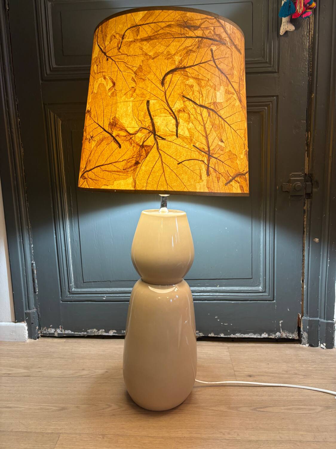Large beige ceramic table lamp with a vintage shade.
