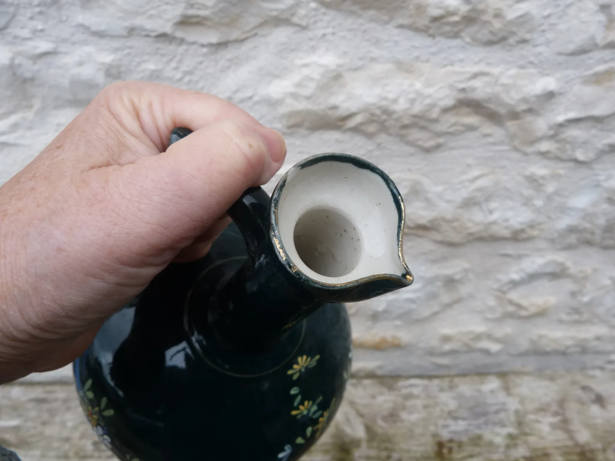 Old ceramic jug with flowers or single-stem vase.
