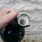 Old ceramic jug with flowers or single-stem vase.