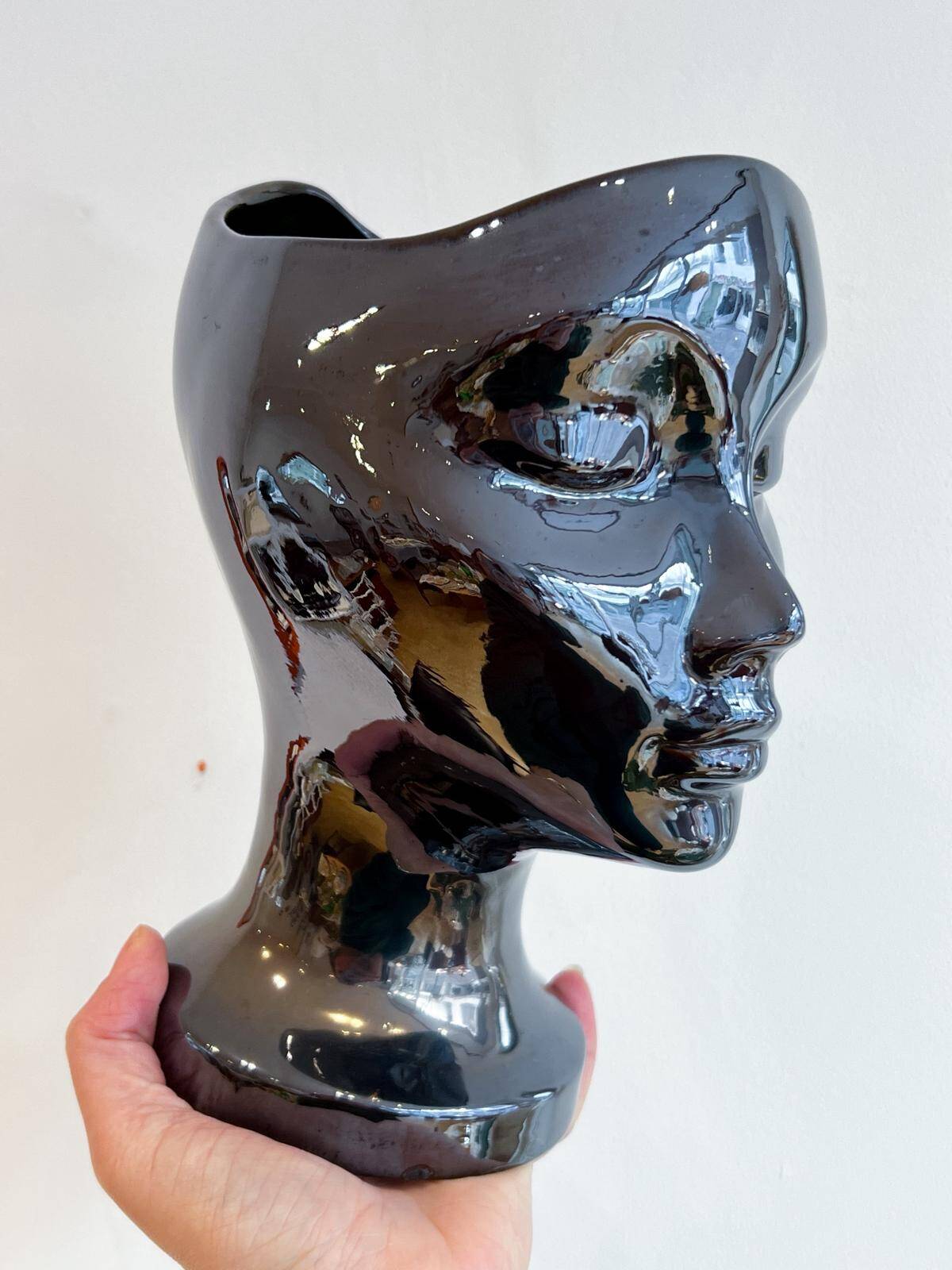 Black ceramic vase with a woman's face.