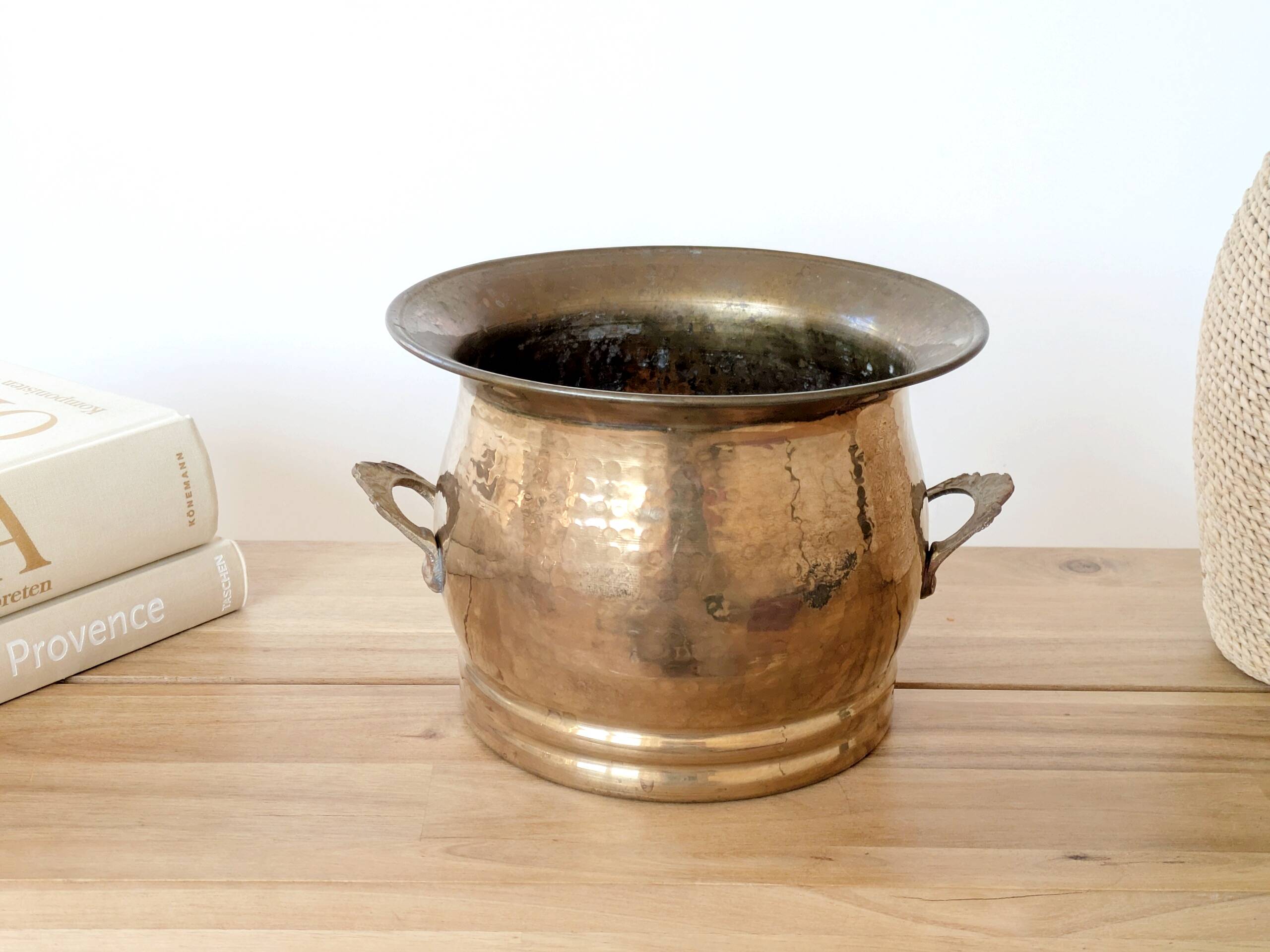 Vintage round cache-pot in hammered brass with decorative handles and patina.