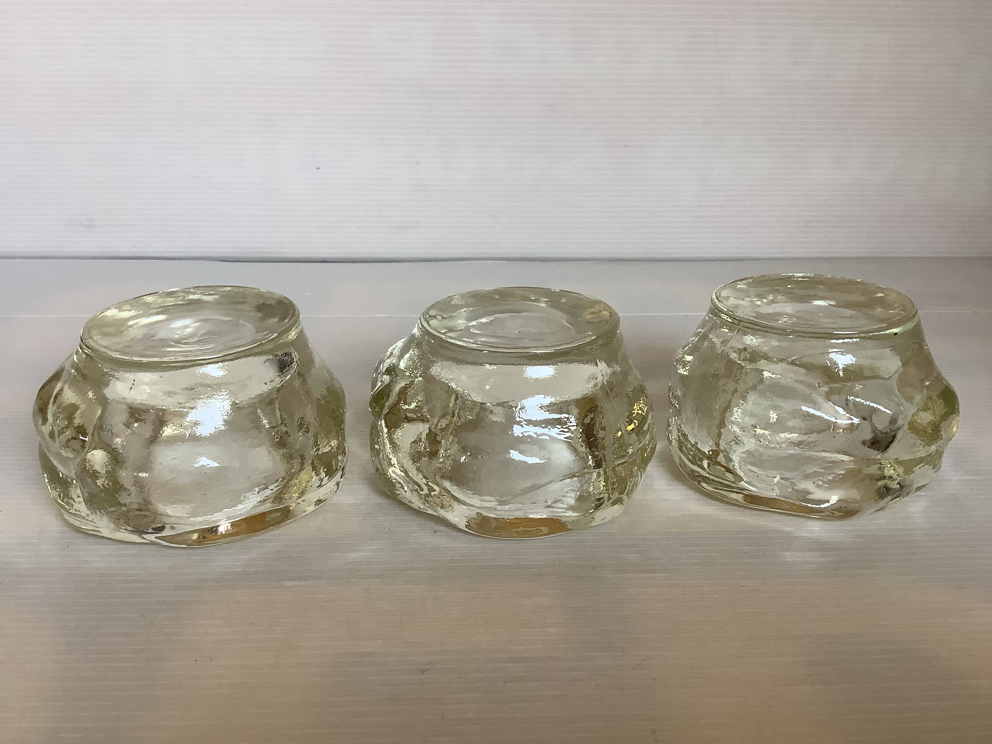 Set of three thick moulded glass candle holders.