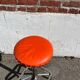 Vintage chrome stool with orange faux leather.
