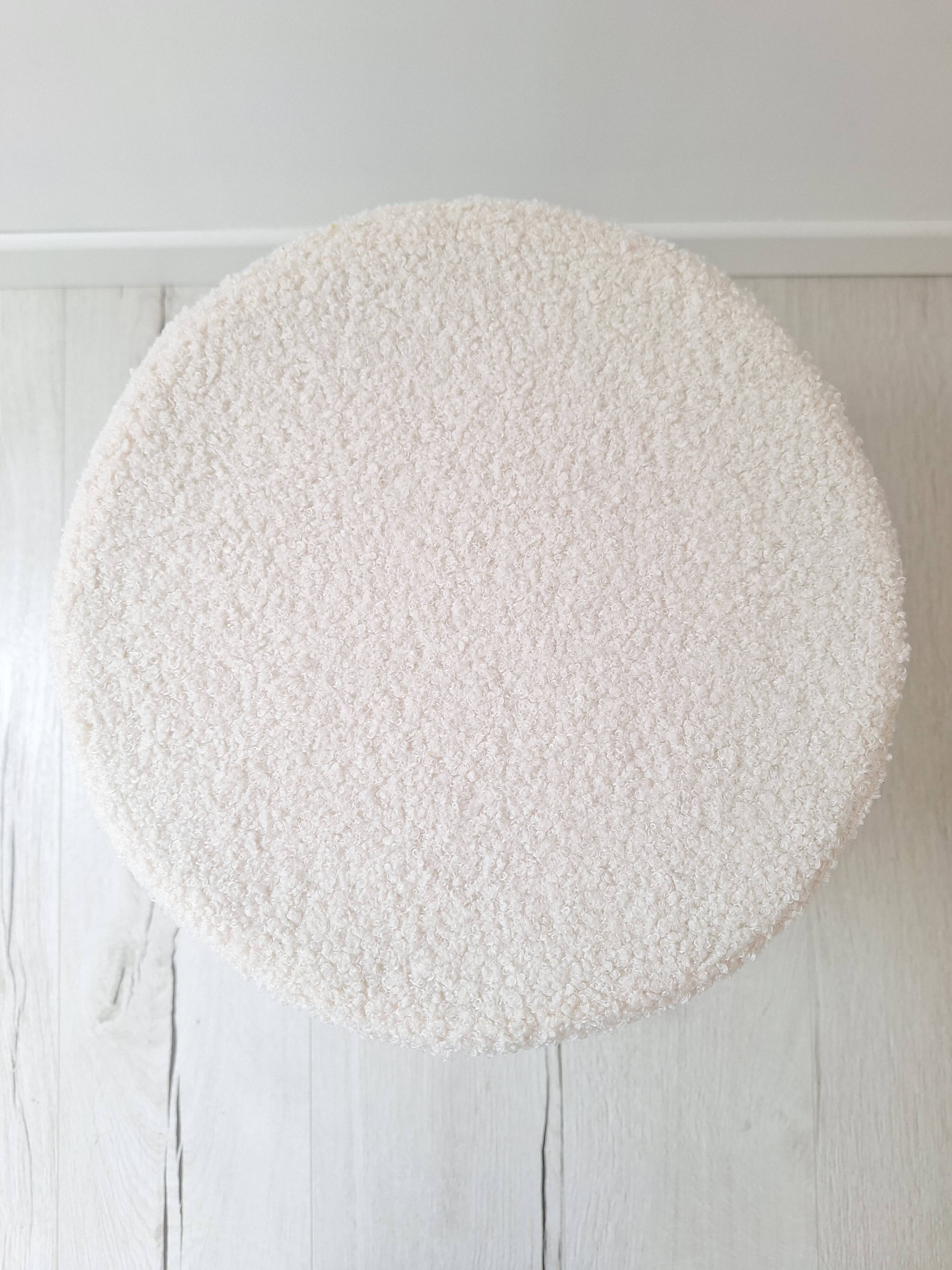 Black iron stool/pouf with its boucle fabric cushion.