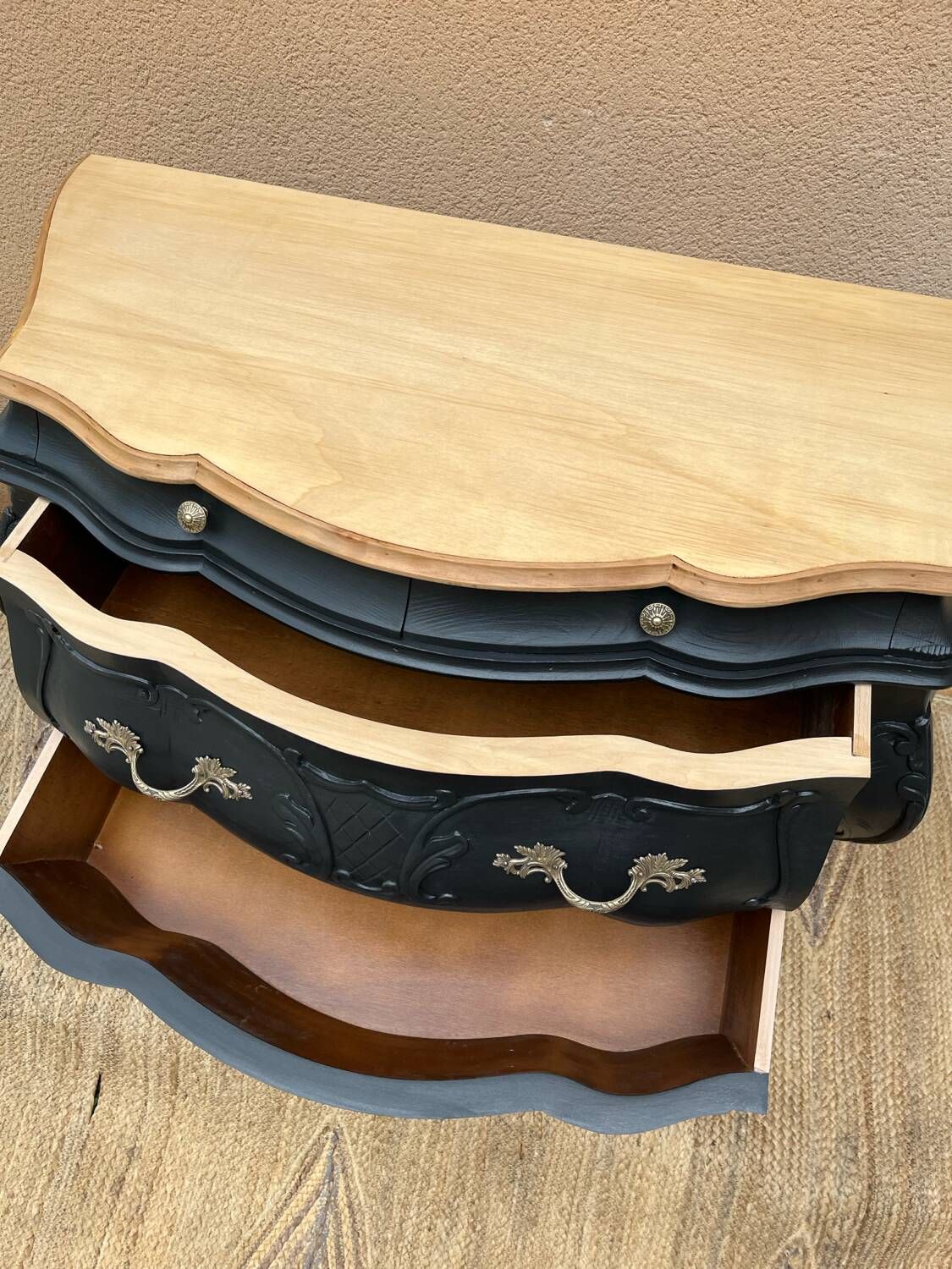 Curved commode painted in black and wood.