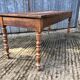 Antique farmhouse table in solid cherry wood with turned legs.