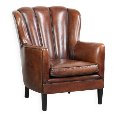 Fauteuil en peau de mouton unique avec des couleurs chaudes et profondes, fini avec un passepoil noir.