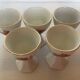 Five old egg cups with orange and grey flowers, polygonal base.