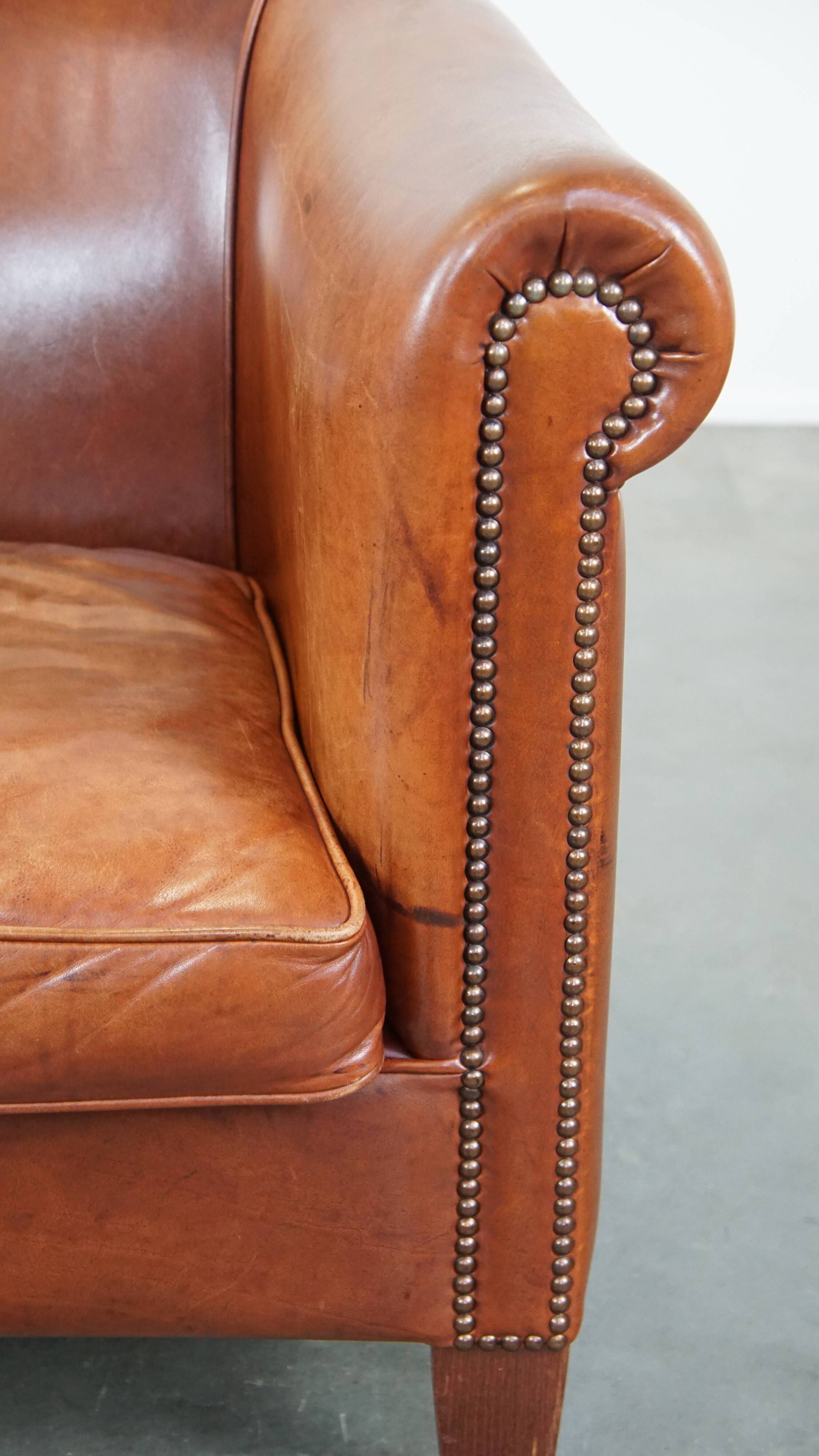 Cognac-colored cow leather club chair finished with decorative nails in English style