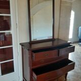 Style set: bevelled mirror and curved wooden chest of drawers.