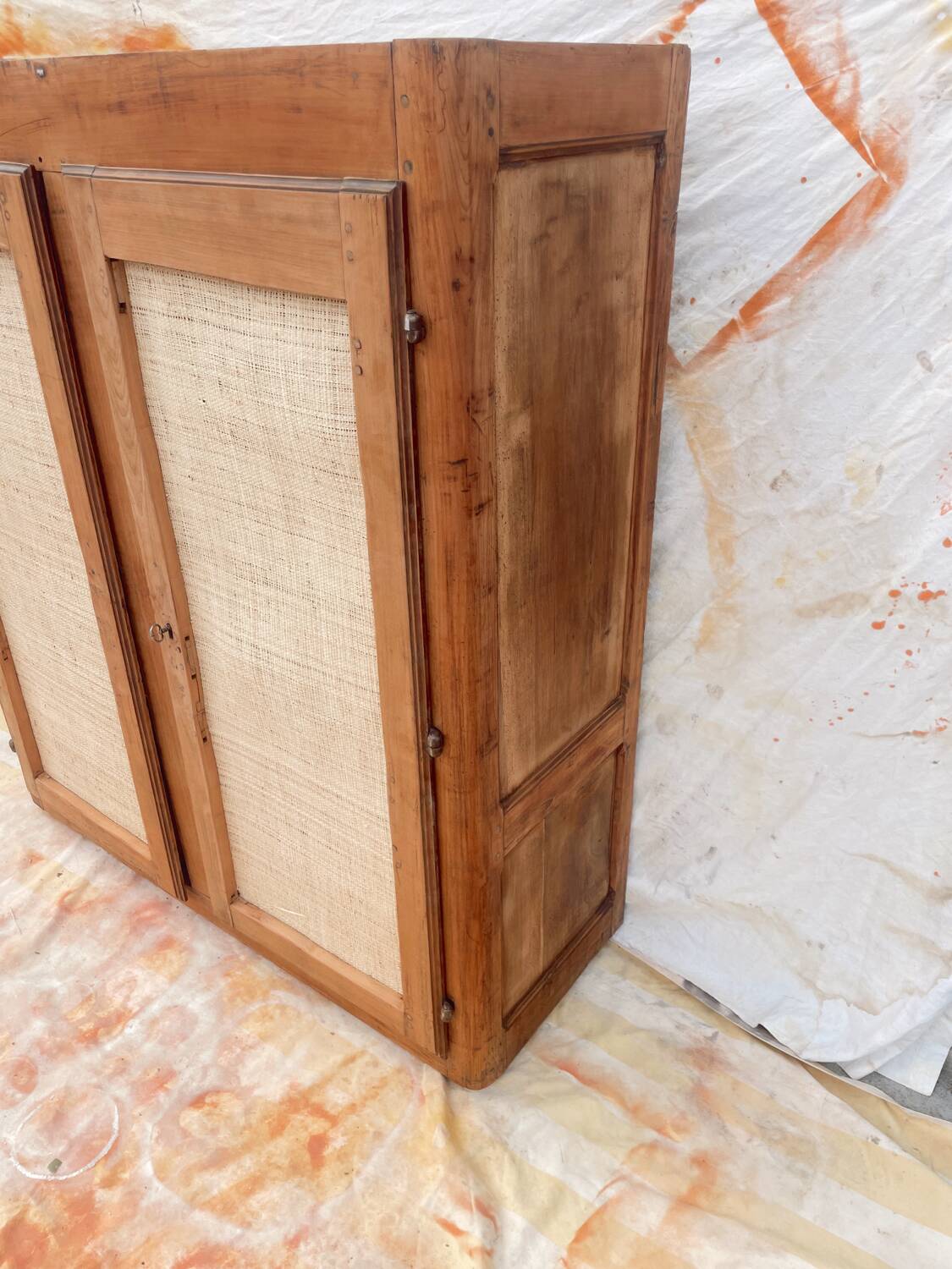 Low cabinet in raw wood and woven raffia.