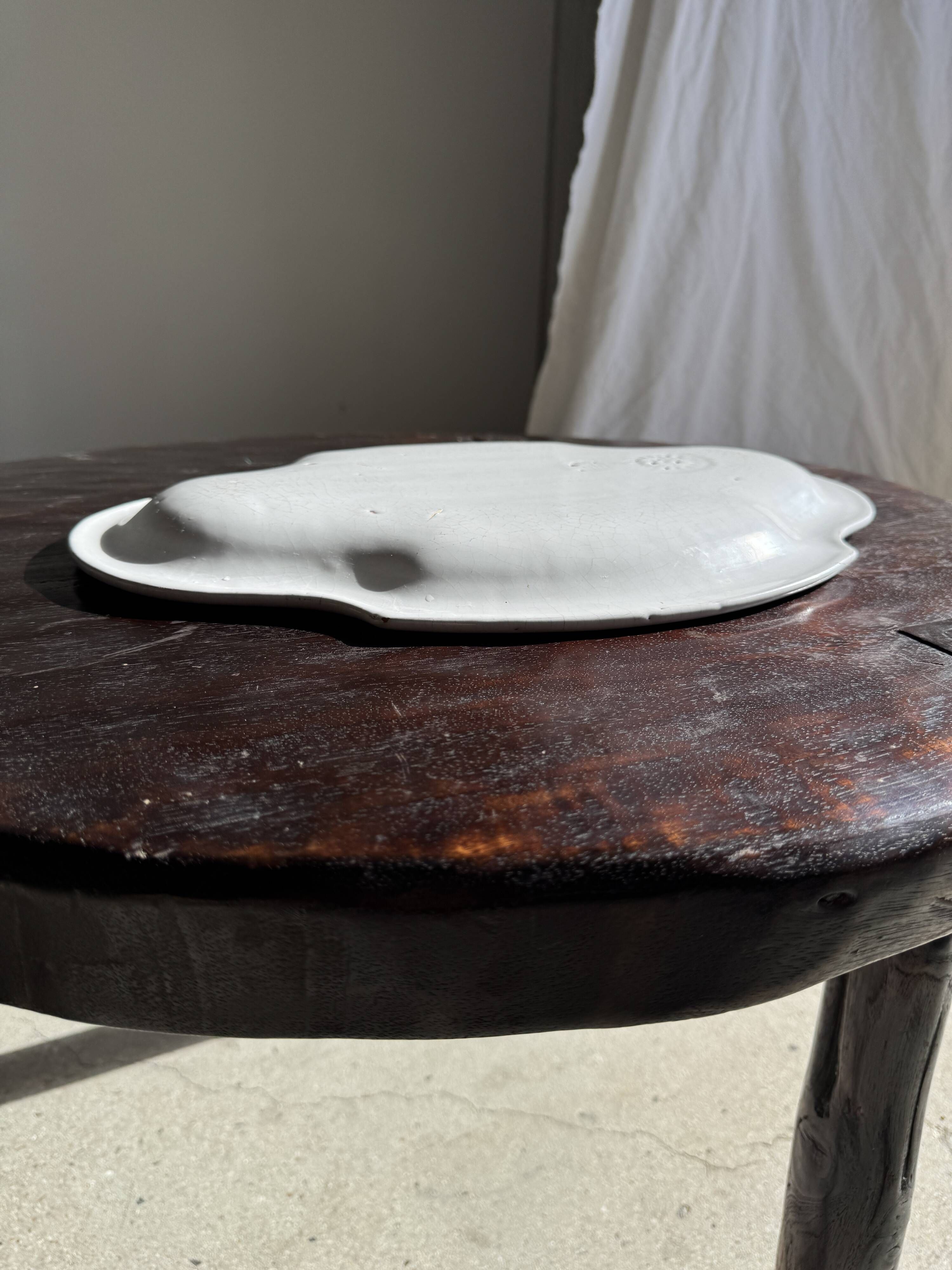 Antique oval-shaped white crackled faience plate with a scalloped edge.